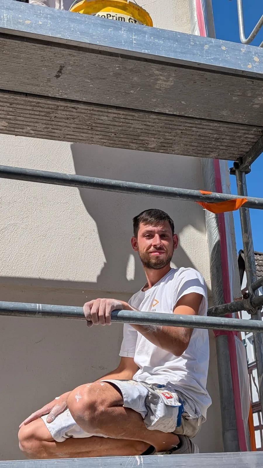 Maler von Malerbetrieb Fischer macht Pause auf dem Gerüst einer Fassade